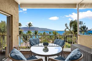 a balcony with a table and chairs and a view of the ocean at Menehune Shores 606 in Kihei