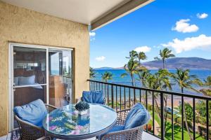 a balcony with a table and chairs and a view of the ocean at Menehune Shores 606 in Kihei +42 photos