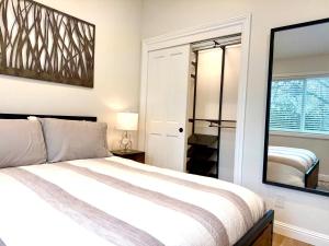 a bedroom with a white bed and a mirror at Chic and Petite 1-Bedroom ADU with Private Entrance in peaceful Orinda in Orinda