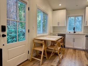 a kitchen with a wooden table and chairs and windows at Chic and Petite 1-Bedroom ADU with Private Entrance in peaceful Orinda in Orinda