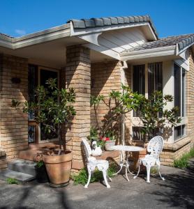 a house with two chairs and a table on the porch at That Retro Place Kiama in Kiama
