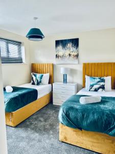 Un dormitorio con dos camas y una mesita de noche. en Spacious 3BR Home in Colchester, with Private Parking, en Colchester 62 fotos más