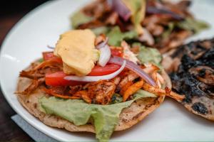 a white plate with a sandwich with crabs and lettuce at Casona de la Guayabera Hospedaje in Tekit