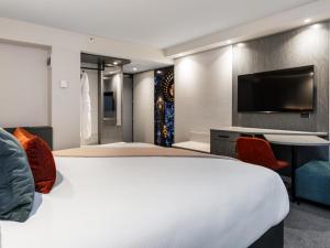 a bedroom with a large bed and a flat screen tv at Millennium Hotel Rotorua in Rotorua