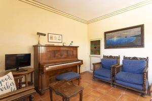 a living room with a piano and blue chairs at S&C Apartments in Ilha da Madeira