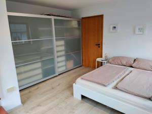 a bedroom with a white bed and glass shelves at Gemütliche Wohnung in Oberteuringen in Oberteuringen