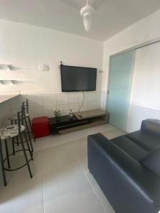 a living room with a couch and a tv on the wall at Apartamento térreo próximo ao Iguatemi in Torto