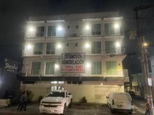 two cars parked in front of a building at night at Hotel Sharidia Inn in Veracruz