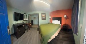 a hotel room with a green bed and a desk at Town & Country Motel in Sioux City