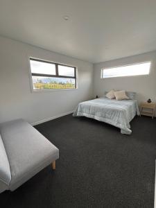 a bedroom with a bed and a couch and two windows at River Terrace Retreat Cromwell in Cromwell