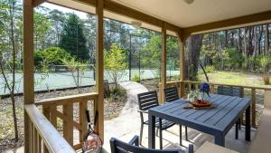 a screened porch with a blue table and chairs at Balmaghie in Bundanoon