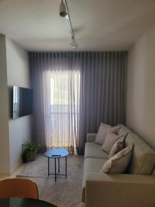 een woonkamer met een bank en een tafel bij Apartamento Urbano 02 dormitórios in Marília
