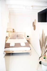 une chambre blanche avec un lit et une télévision à écran plat dans l'établissement Studio in the Heart of Mykonos Town, à Mykonos
