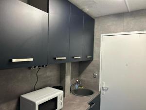 a kitchen with black cabinets and a sink and a microwave at STUDIO - 4pers PROCHE GARE 10 MIN DISNEY in Bussy-Saint-Georges