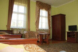 een slaapkamer met een bed, een tv en 2 ramen bij Pałac w Nosowie in Nosowo