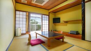 a living room with a table and a large window at Ryokan Hirayama in Ueki
