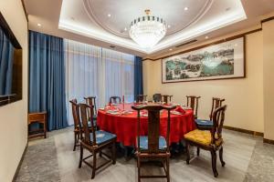 uma sala de jantar com uma mesa com cadeiras e um lustre em Century Runhua Hotel em Jinan