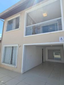 a large white house with two windows and a garage at Casa duplex, 400m da praia e 13min do Beto Carrero in Piçarras