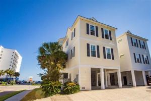a white house with a palm tree in front of a building at 6BR Luxury Vacation Home - Unbeatable Location and View in Myrtle Beach