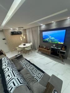 a living room with a couch and a large screen tv at Apt-igorss-aju in Aracaju
