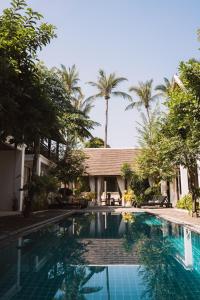 a swimming pool in front of a house with palm trees at Le Sen Boutique Hotel in Luang Prabang