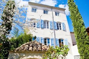 a white building with blue windows and a roof at Elegant Town house-sleeps 14 in Saint-Hippolyte-du-Fort