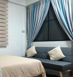 a bedroom with a blue couch and a window at Summer Homestay@civic centre in Sibu