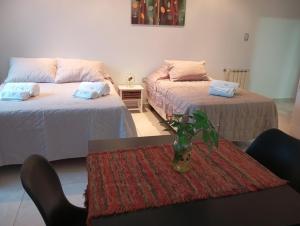 a room with two beds and a table with a vase at Prunus departamentos in Comodoro Rivadavia