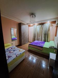 a bedroom with two beds and a chandelier at 2 Bedrooms Apartment beside American University in New Cairo in Cairo