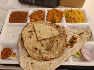 a white tray with a plate of food with tacos and dips at Eve Service apartment in Mysore