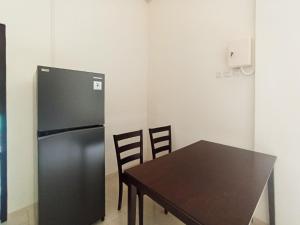 a kitchen with a black refrigerator and a table at De Corner 2 Madiun RedPartner in Madiun