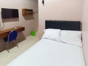 a bedroom with a bed and a desk and a television at De Corner 2 Madiun RedPartner in Madiun