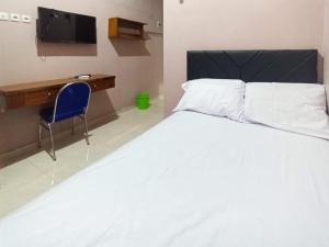 a bedroom with a bed and a desk and a tv at De Corner 2 Madiun RedPartner in Madiun