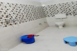 a bathroom with a toilet and a blue trash can at Hotel Shri Kedar Mangalam By StayApart in Phata