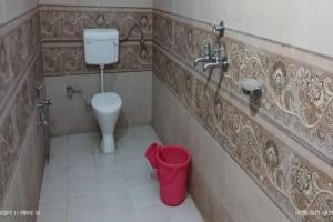a bathroom with a toilet and a sink and a trash can at Hotel Shri Kedar Mangalam By StayApart in Phata +10 photos