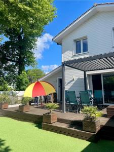 eine Terrasse mit einem bunten Regenschirm vor einem Haus in der Unterkunft La maison de CASTETS entre forêt et océan in Castets