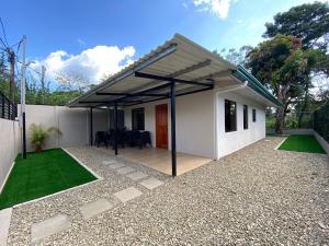 a small white house with a patio and grass at Casa Mi Puerto in Puerto Jiménez