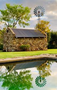 a stone barn with a windmill and a pond at Vergeet-My-Niet in Prince Albert