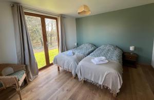 a bedroom with two beds and a large window at Les Galets 1 in Auchonvillers