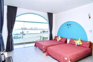 two beds in a room with a large window at Xing Ocean Vũng Tàu in Vung Tau