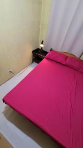a large pink bed with a table in a room at Cozy Casa in the City Center in Baguio