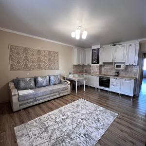 a living room with a couch and a kitchen at Момышулы 28-410 две комнаты in Fëdorovka