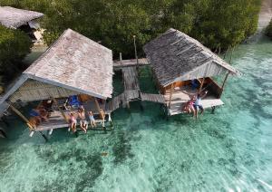 an aerial view of people sitting on benches in the water at Manta Homestay - Raja Ampat in Airborei