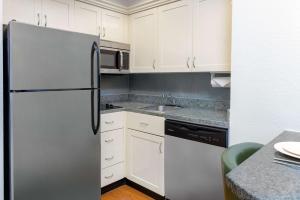a kitchen with white cabinets and a stainless steel refrigerator at Homewood Suites by Hilton Bonita Springs, FL in Bonita Springs