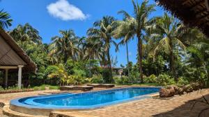 a swimming pool in front of a resort with palm trees at AR Sun Hotel in Antsiranana