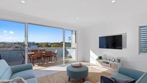Una sala de estar con un sofá y un televisor. en Boronia Beach House Three, en Sawtell