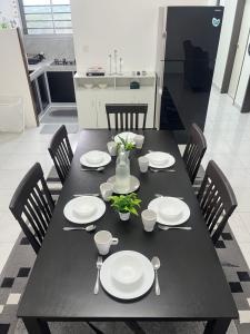 a black dining room table with white plates and utensils at Condominium Seri Alam, Masai #ANhome in Masai