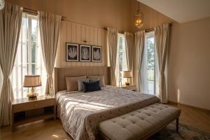 1 dormitorio con 1 cama con 2 lámparas y ventanas en LohonoStays Villa Lanai, en Arpora