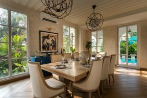 a dining room with a wooden table and chairs at LohonoStays Villa Lanai in Arpora