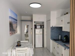 a kitchen with white cabinets and a white refrigerator at La Pinède Océane,400m des plages in Mimizan